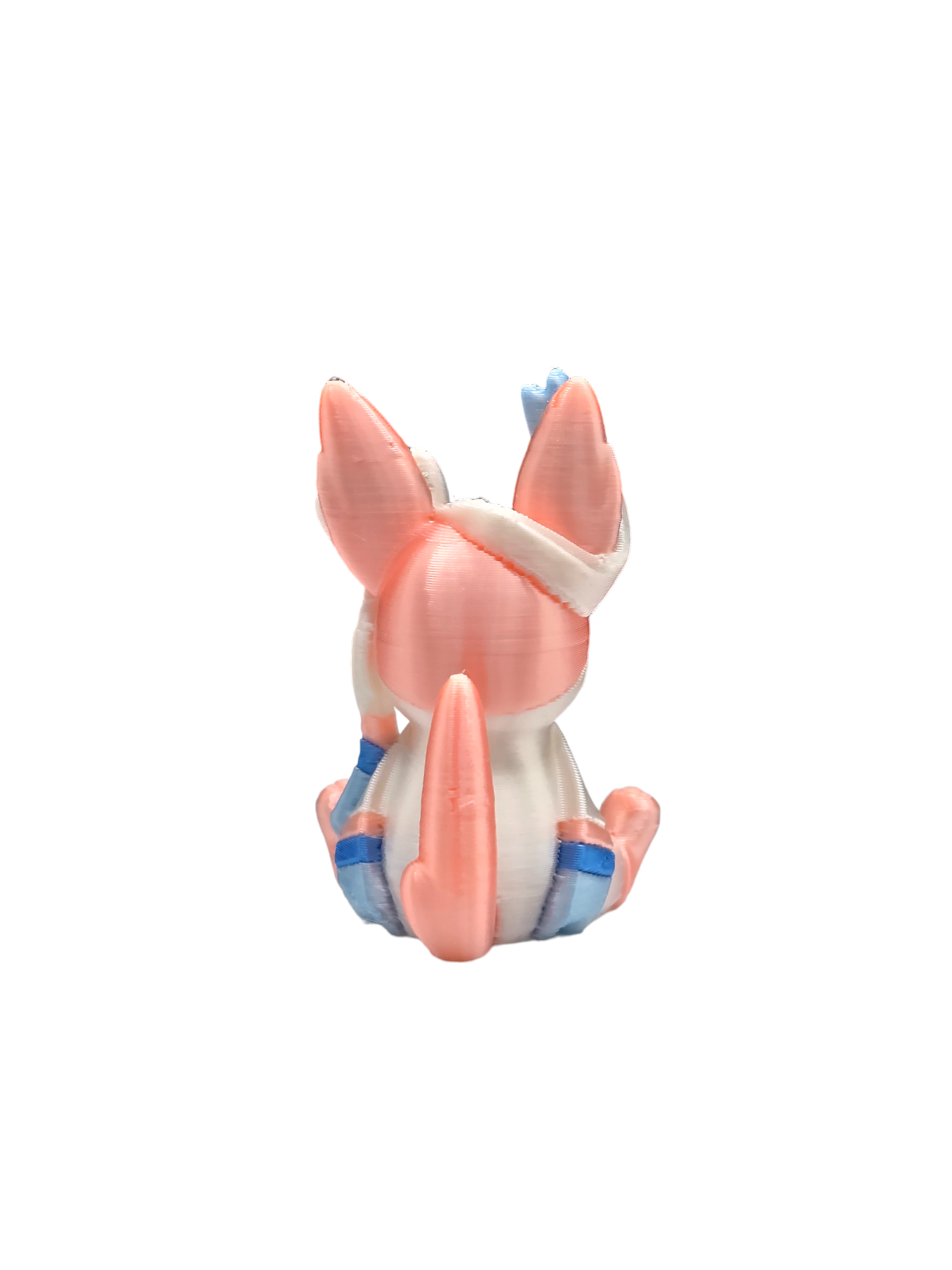 a pink and blue toy animal sitting on top of a white surface